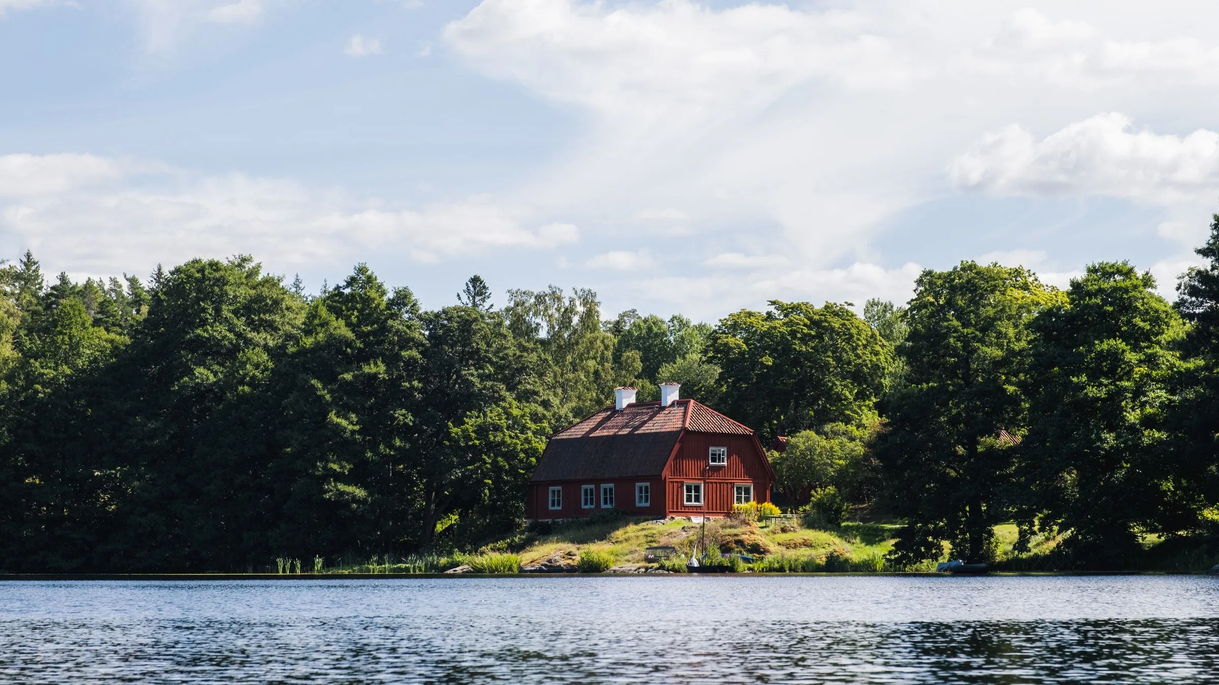 Rött hus vid en sjö med skog runt omkring